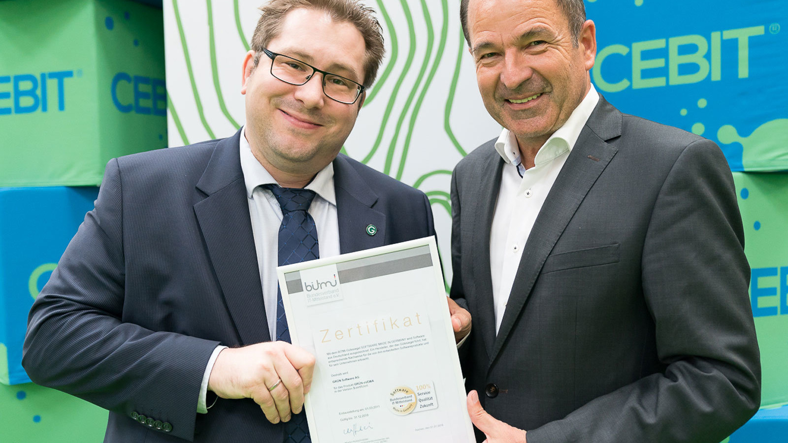 Olivier Chatain, Sales Director der GRÜN Software AG, nimmt die BITMi-Gütesiegel von Martin Hubschneider, Vizepräsident und Vorstand des BITMi, entgegen.